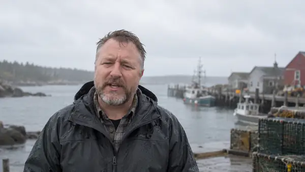 A presenter speaks outside during a rainy day, portrait video framing.