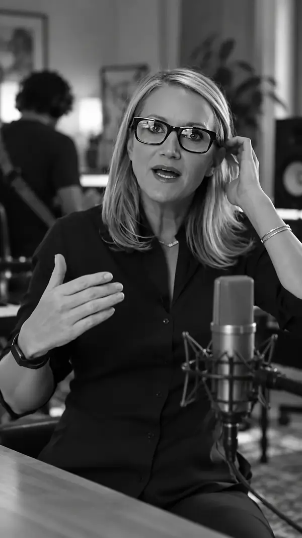 A presenter speaks while music plays nearby in a vertical video.